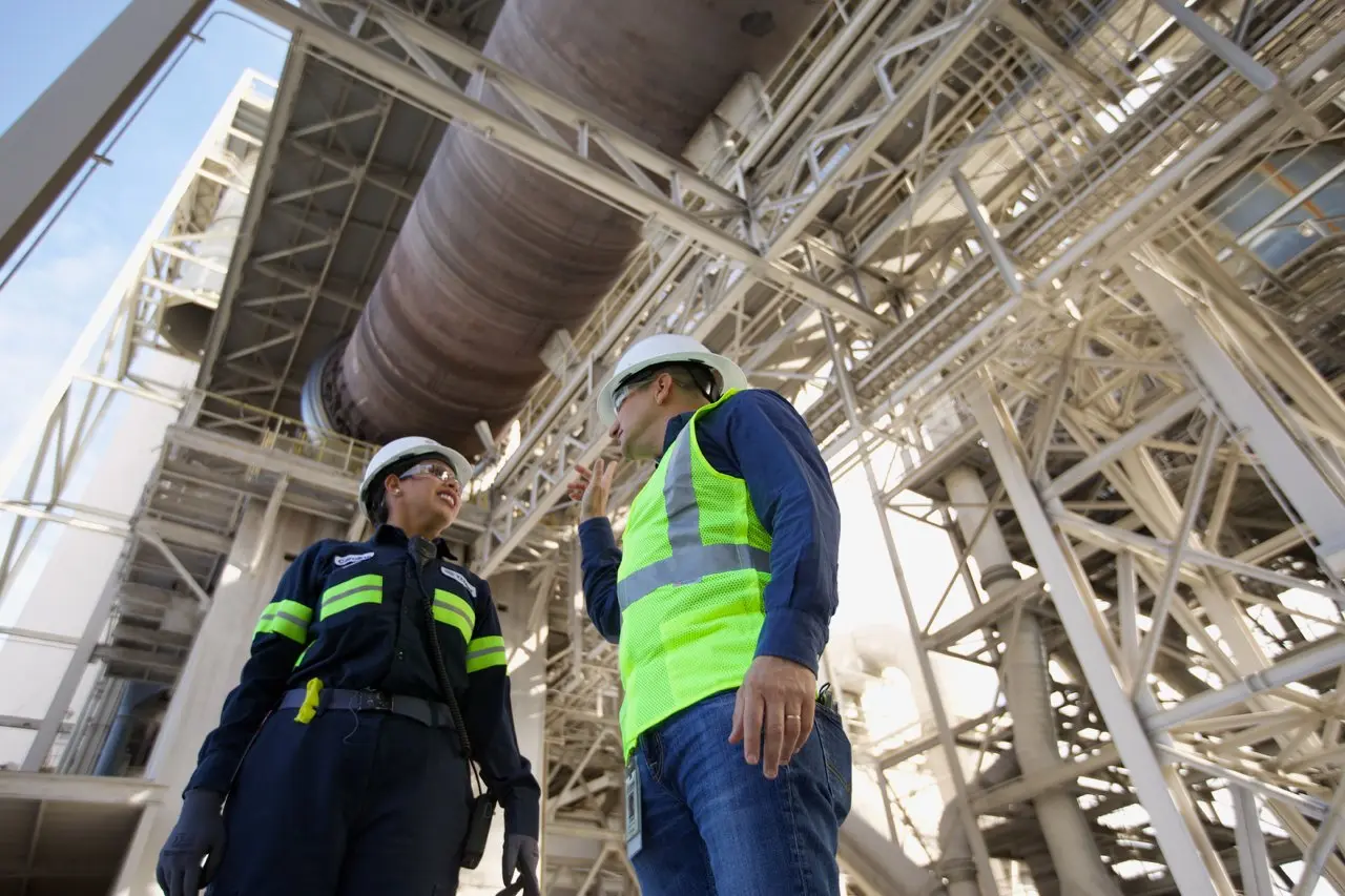 Cement plant maintenance team discussing operations near industrial equipment